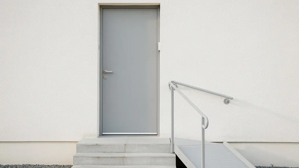 Entrée de maison avec trois marches et une rampe d’accès discrète, dans une ambiance extérieure minimaliste.